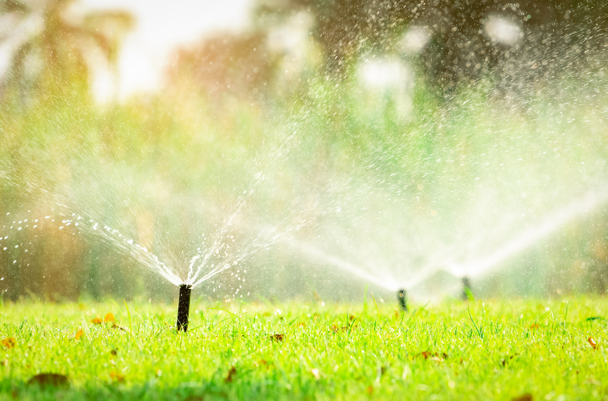 Automatic lawn sprinkler watering green grass. Sprinkler with automatic system. Garden irrigation system watering lawn. Sprinkler system maintenance service. Home service irrigation sprinkler.